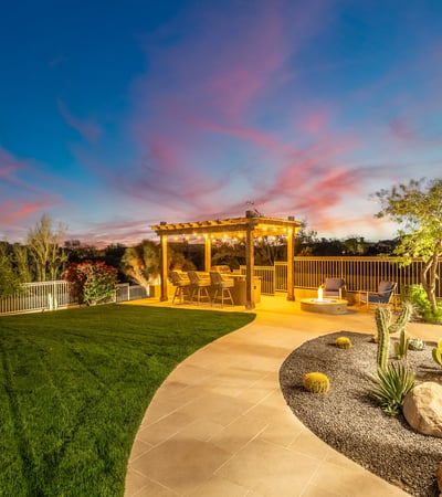 Beautifully designed Scottsdale backyard with manicured grass, desert landscaping, and pergola space ideal for relaxing or entertaining.