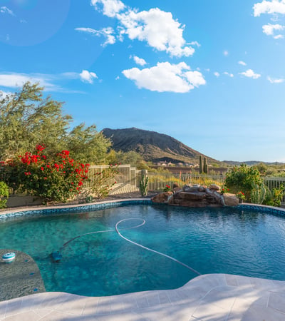 Scottsdale pool with rock waterfall feature, desert landscaping, and mountain views, offering a serene and private outdoor setting.