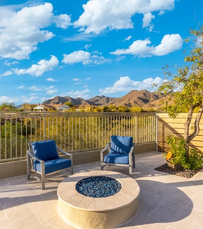 Cozy Scottsdale patio with fire pit and seating area overlooking scenic mountain views and desert landscape.