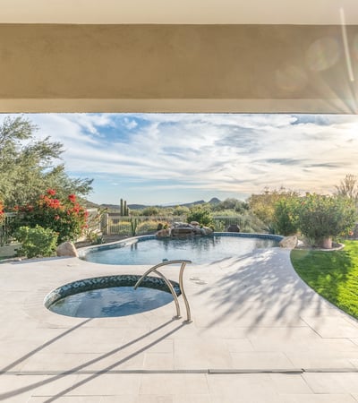 Scottsdale covered patio overlooking pool and spa with landscaped surroundings and mountain views, ideal for relaxing outdoors.