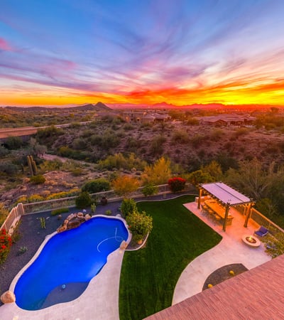 Scottsdale aerial capturing expansive desert scenery, nearby homes, and vibrant sunset skies.