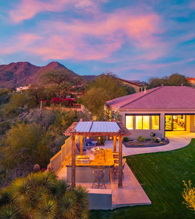 Scottsdale outdoor living space with covered patio, lawn, and outdoor kitchen, complemented by scenic mountain views.