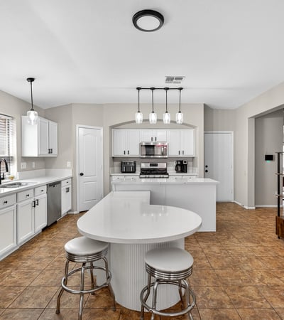 Functional kitchen with breakfast bar, white cabinets, and modern appliances. Seamless connection to living areas enhances flow in this Casa Grande home.