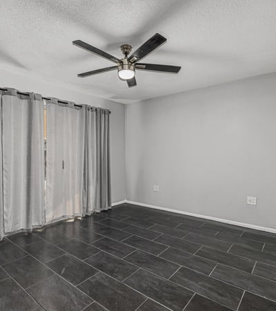 Bright bedroom with tile flooring, ceiling fan, and natural light. This Sun City home offers updated finishes and flexible room options.