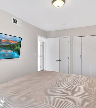 Scottsdale bedroom with wall-mounted TV, neutral tones, and practical layout, offering a comfortable and functional retreat.