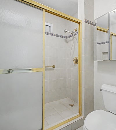 This bathroom features a spacious walk-in shower with glass enclosure, tile finishes, and convenient accessibility enhancements. The clean design offers both practicality and long-term usability.