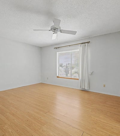 This spacious primary suite features neutral finishes, durable flooring, and abundant natural light. The flexible floorplan allows for comfortable furnishings while creating a peaceful retreat within the home.