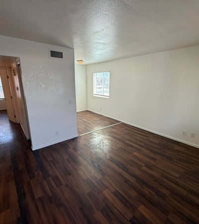 Large living room with rich wood-look flooring, neutral finishes, and a bright open feel. The spacious layout creates a welcoming environment ideal for entertaining guests or enjoying everyday comfort.
