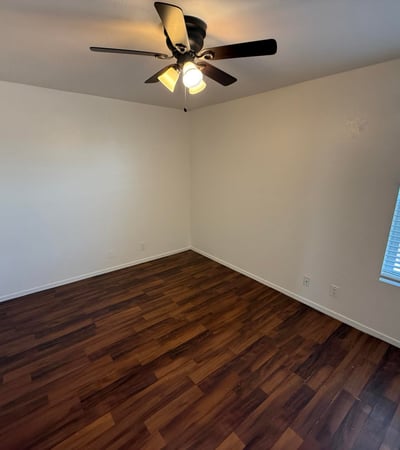 Bright and airy bedroom offering wood-look flooring, ceiling fan, and natural light. This versatile space works well as a guest room, home office, or primary sleeping area.