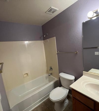 Full bathroom featuring a tub and shower combination, vanity storage, and easy-care finishes. Designed to comfortably accommodate guests and everyday household use.