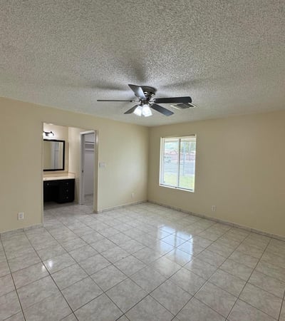 Large primary suite with room for oversized furnishings, ceiling fan, and private bathroom access. A comfortable retreat designed for relaxation and convenience.