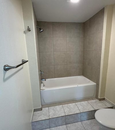 Well-sized bathroom featuring a tub and shower combination with updated tile surround and practical layout. Designed to provide comfort, convenience, and easy maintenance.