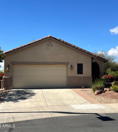Charming front exterior with mature desert landscaping, spacious driveway, two-car garage, and attractive paver accents creating beautiful curb appeal in a desirable Buckeye neighborhood.