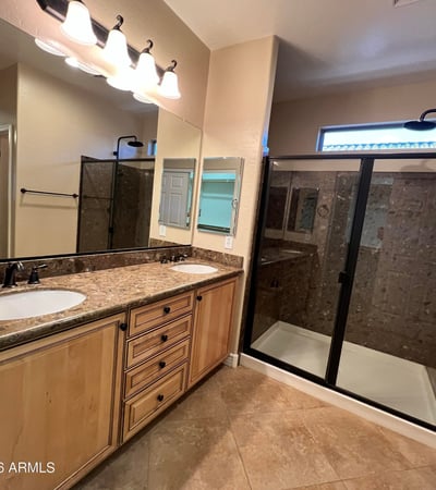 Beautiful primary bath offering dual vanities, abundant cabinetry, upgraded countertops, modern fixtures, and a spacious tiled walk-in shower. A relaxing retreat designed with both comfort and functionality in mind.
