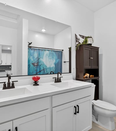 Stylish hall bathroom featuring dual vanities, quartz countertops, modern cabinetry, black fixtures, and plenty of storage for convenient everyday use.