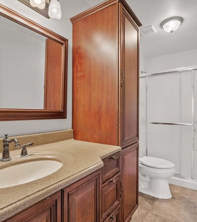 Updated cabinetry, modern fixtures, framed mirror, and a sliding glass shower enclosure create a clean and functional bathroom serving the secondary living spaces.