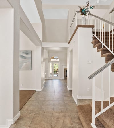A soaring two-story entry welcomes guests with elegant tile flooring, natural light, and a sweeping staircase. The spacious foyer sets the tone for the home's open and inviting floor plan.