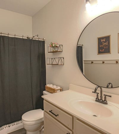 Clean and inviting hall bathroom with a spacious vanity, updated lighting, modern fixtures, and a convenient tub/shower combination serving the secondary bedrooms.