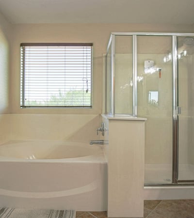 Relaxing primary bathroom featuring a deep soaking tub, separate glass shower, natural light, and spacious layout. Designed to provide both comfort and convenience in this Waddell home.