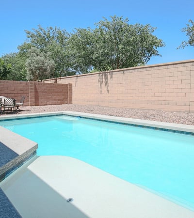 Inviting backyard pool featuring a spacious tanning ledge, modern design, and relaxing patio space. A wonderful outdoor feature that enhances the lifestyle offered by this Waddell property.
