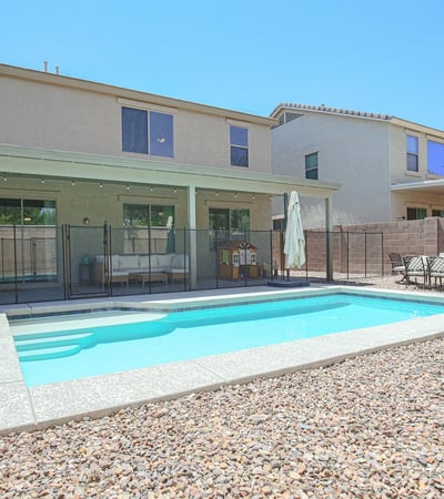 Backyard retreat showcasing a modern swimming pool, safety fence, expansive patio, and easy-care landscaping. Designed for both relaxation and entertaining at this Waddell property.
