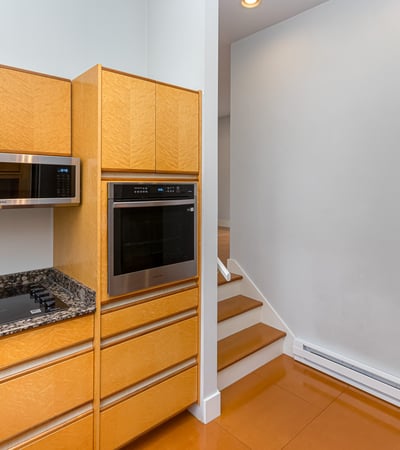 Modern kitchen features sleek cabinetry, high-end appliances, and an open layout leading to inviting stairs.