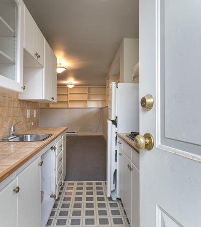 Spacious kitchen with ample cabinetry and tile countertops, leading into an inviting, open living space.