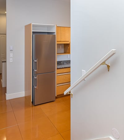Discover a modern entryway leading to an open kitchen, featuring sleek appliances and contemporary finishes.