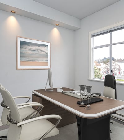 Modern office space featuring a sleek desk, ample natural light, and a minimalist aesthetic.