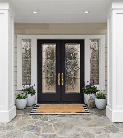 Inviting entrance featuring decorative beveled glass doors, vibrant planters, and a tasteful stone pathway, perfect for welcoming guests.