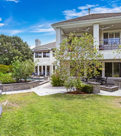 Spacious home with lush gardens, multiple outdoor seating areas, and a beautifully landscaped yard for relaxation.