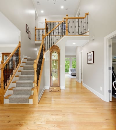 Bright and inviting entryway featuring a spacious layout, hardwood floors, and a sweeping staircase.