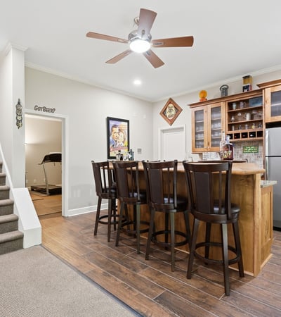 Spacious entertainment area featuring a modern kitchen bar with ample seating and convenient staircase access.