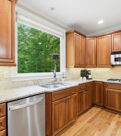 Bright kitchen featuring custom wood cabinetry, modern appliances, and ample counter space overlooking a lush outdoor view.