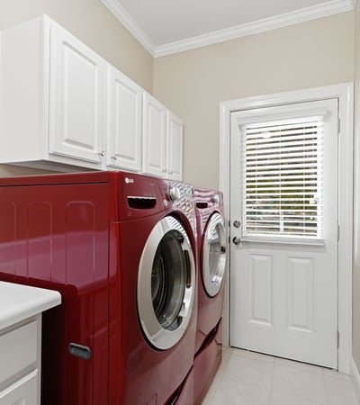 Bright and functional laundry room featuring modern red appliances and ample storage space.