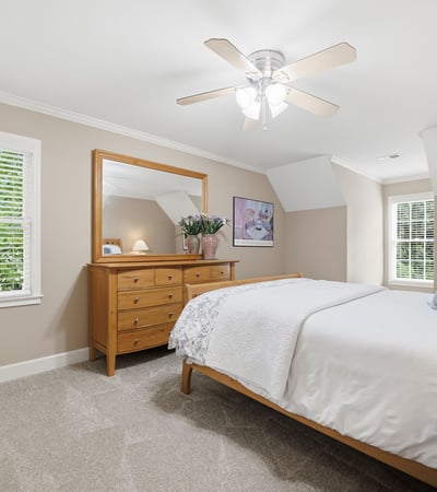 Bright and airy bedroom featuring natural light, modern ceiling fan, and ample storage in a cozy setting.