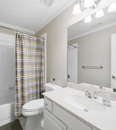 Bright and functional bathroom featuring a shower-tub combo, modern vanity, and ample storage options.