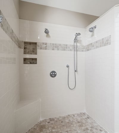 Spacious, modern shower with multiple showerheads and built-in shelving, ideal for a refreshing experience.