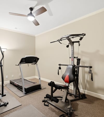 Spacious workout room featuring modern fitness equipment and ample natural light, perfect for home exercise routines.