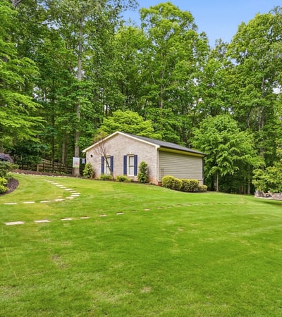 Nestled among lush trees, this property features expansive green space and a versatile outbuilding.