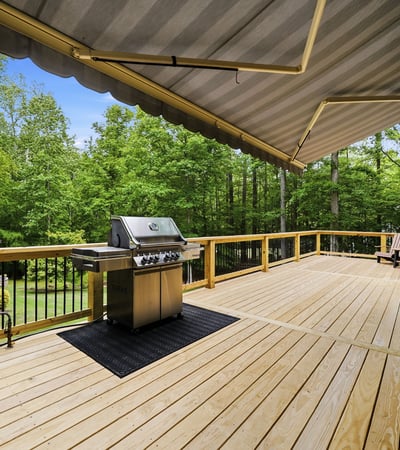 Expansive deck with built-in grill, surrounded by lush greenery, perfect for outdoor gatherings and relaxation.
