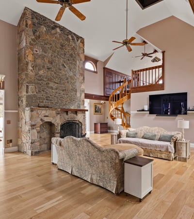 Spacious living area featuring a dramatic stone fireplace and a cozy open layout. Perfect for gatherings.