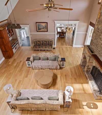 Spacious living area with vaulted ceilings, a rustic stone fireplace, and abundant natural light throughout.