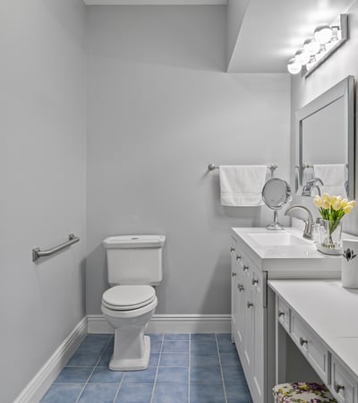 Bright and functional bathroom featuring modern fixtures, ample storage, and sleek blue tile flooring.