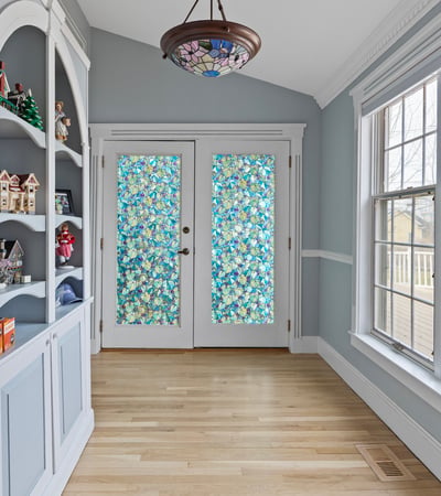 Bright and inviting sunroom with unique stained glass doors and built-in shelving for added character.