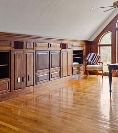Bright, spacious office featuring wooden paneling, ample storage, and large windows for natural light.