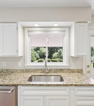 Modern kitchen with granite countertops, ample natural light, and views of the beautifully landscaped yard.
