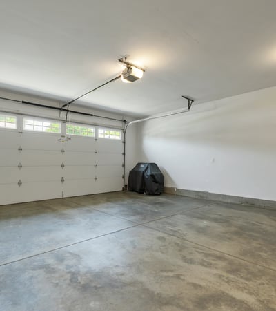 Spacious garage with ample storage potential, featuring a large door and well-lit interior.