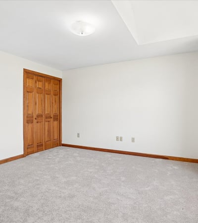 Spacious room filled with natural light, featuring neutral tones and ample storage options for versatile use.