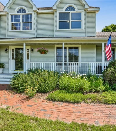 Spacious front porch with landscaped garden offers inviting outdoor space for relaxation and gatherings.